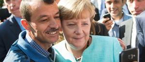 Ein Symbolbild der Willkommenskultur: Bundeskanzlerin Angela Merkel posiert beim Besuch einer Erstaufnahmeeinrichtung Berlin-Spandau für ein Selfie mit einem Flüchtling.