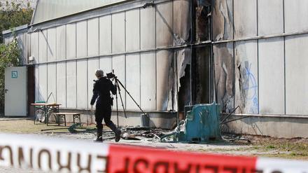 Eine Kriminalpolizistin untersucht am Sonntag in Friemar (Thüringen) nach einem Feuer in einer Notunterkunft für Flüchtlinge den Brandort. Nach Angaben der Polizei brach das Feuer am frühen Sonntagmorgen an mobilen Toiletten aus.