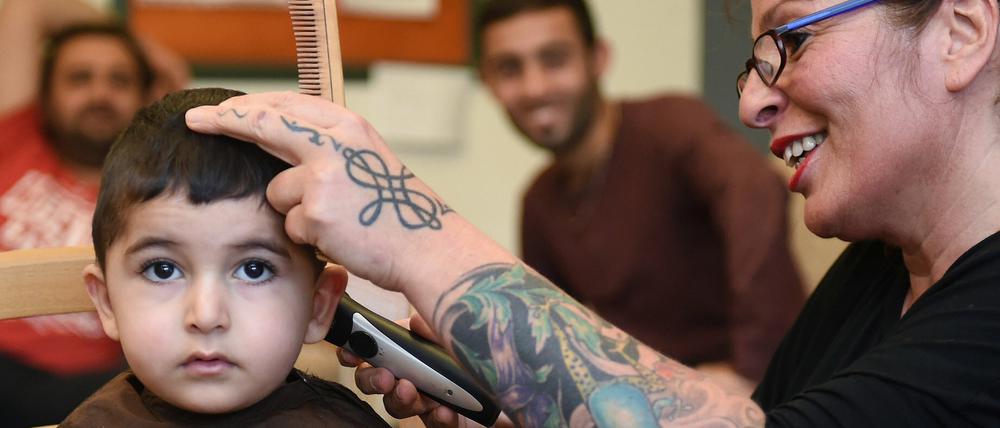 Friseurin Susanne Toraman schneidet am 28.09.2015 in Bremen dem zweijährigen Masoum aus Syrien die Haare. Einmal die Woche schneidet Toraman Flüchtlingen in einem Übergangswohnheim kostenlos die Haare.