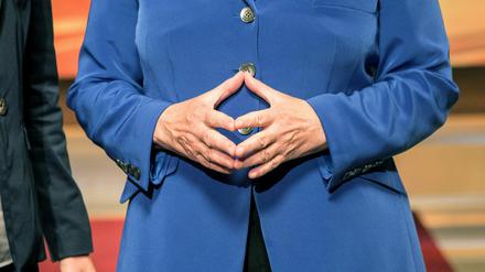 Bundeskanzlerin Angela Merkel (CDU) steht mit zur Raute geformten Händen neben TV-Moderatorin Anne Will.