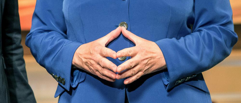 Bundeskanzlerin Angela Merkel (CDU) steht mit zur Raute geformten Händen neben TV-Moderatorin Anne Will.