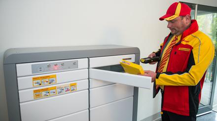 Paketzusteller Marko Zimmermann steht vor einem Paketkasten für Mehrfamilienhäuser in einer Wohnanlage in Berlin. 