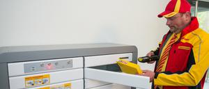 Paketzusteller Marko Zimmermann steht vor einem Paketkasten für Mehrfamilienhäuser in einer Wohnanlage in Berlin. 