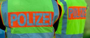 Polizisten tragen Warnwesten mit der Aufschrift "Polizei". 