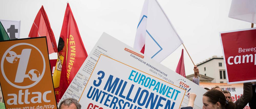 Verschiedene Aktionsbündnisse stehen mit Fahnen und Transparenten vor dem Brandenburger Tor in Berlin, um für eine geplante Großdemonstration am 10.10.2015 gegen die Handelsabkommen TTIP und CETA zu werben.