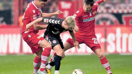 Nimm du ihn, ich hab ihn sicher. Die Unioner Damir Kreilach (l.) und Michael Parensen (r.) beackern St. Paulis Marc Rzatkowski. Nicht immer setzten sich die Köpenicker in den Zweikämpfen durch. 