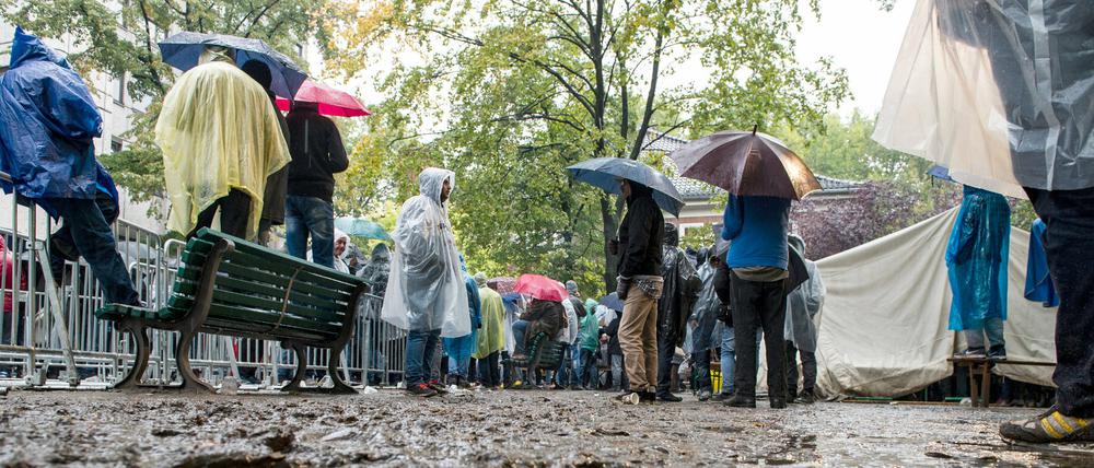 Bei Regen warten Flüchtlinge auf dem Gelände des Landesamts für Gesundheit und Soziales (Lageso) in Berlin, registriert zu werden.