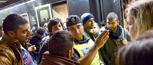 Flüchtlinge werden im Bahnhof in Stockholm von einem Polizisten weitergeleitet.