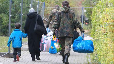 Ein Bundeswehrsoldat hilft Flüchtlingen aus Syrien beim Tragen ihrer Habseligkeiten vor der Flüchtlingsunterkunft in Gera. Die Bundesregierung überlegt, die Soldaten künftig auch für Abschiebungen einzusetzen.