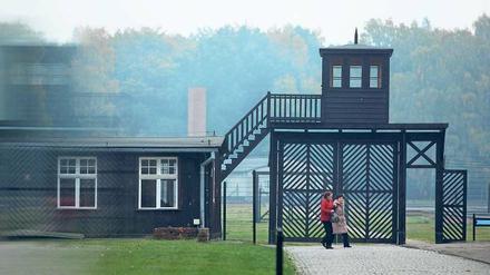 Vor dem Eingangstor eines ehemaligen deutschen Konzentrationslagers in Polen gehen zwei Frauen einen Weg entlang.