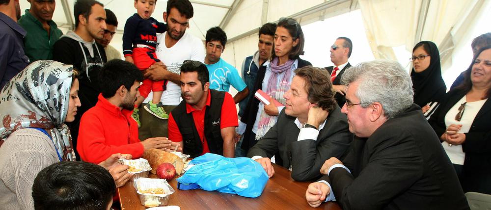 Der Außenminister der Niederlande Bert Koenders (2. von rechts) spricht in einem Zeltlager in Griechenland mit Flüchtlingen.