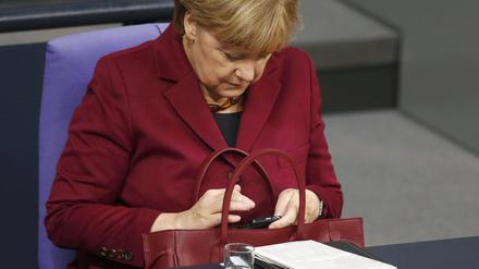 Bundeskanzlerin Angela Merkel schaut kurz mal auf ihr Handy.