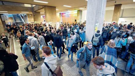Studierende laufen suchend durch das Foyer eines Universitätsgebäudes.