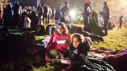 Flüchtlingskinder essen am Mittwoch auf einer Wiese an der deutsch-österreichischen Grenze in Österreich vor Wegscheid und warten auf ihre Einreise nach Deutschland.