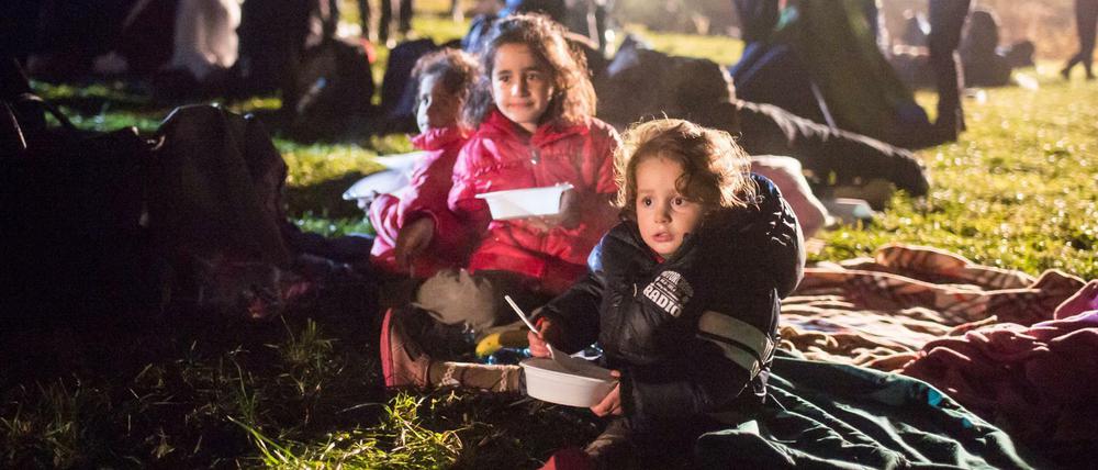 Flüchtlingskinder essen am Mittwoch auf einer Wiese an der deutsch-österreichischen Grenze in Österreich vor Wegscheid und warten auf ihre Einreise nach Deutschland.