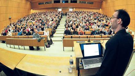 Ein Professor steht vor Studierenden in einem Hörsaal.