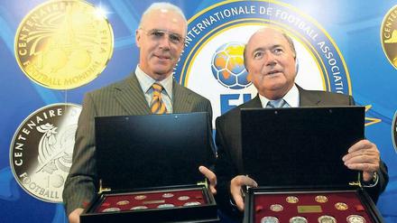 Was kann man hier noch für bare Münze nehmen? Franz Beckenbauer und Fifa-Präsident Joseph Blatter stellen 2004 Gedenkmünzen für die WM 2006 vor. 