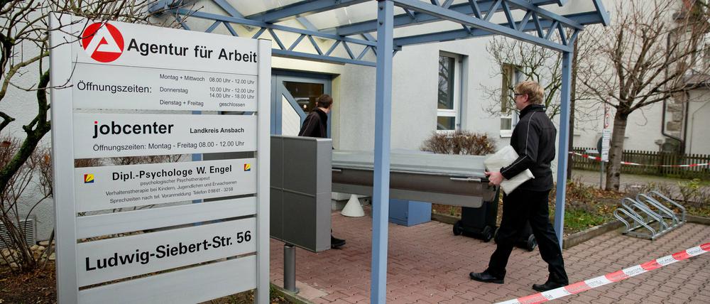 Mitarbeiter eines Bestattungsunternehmens tragen am 03.12.2014 in Rothenburg ob der Tauber (Bayern) einen Sarg in ein Jobcenter. Ein Mann hatte zuvor in dem Jobcenter einen 61-jährigen Mitarbeiter der Behörde erstochen.