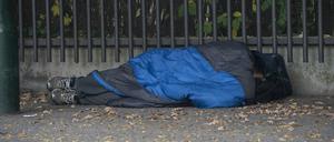 Ein Obdachloser liegt in einem Schlafsack gehüllt unter einem Dachvorsprung vor dem Berliner Zoo.
