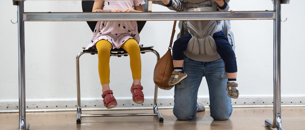 Eine junge Mutter mit zwei Kinder kniet hinter der Wahlkabine in der Jane-Addams-Schule in Friedrichshain und füllt ihre Stimmzettel aus. +++ dpa-Bildfunk +++