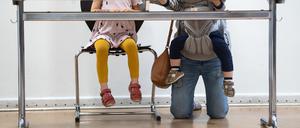 Eine junge Mutter mit zwei Kinder kniet hinter der Wahlkabine in der Jane-Addams-Schule in Friedrichshain und füllt ihre Stimmzettel aus. +++ dpa-Bildfunk +++