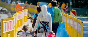 Flüchtlinge gehen mit ihrem Hab und Gut in Gießen (Hessen) über eine Straße zur Zentralen Erstaufnahmeeinrichtung des Landes. Auf dem Kasernengelände am Stadtrand sind tausende Flüchtlinge untergebracht.