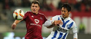 Nürnbergs Alessandro Schöpf (links) und der Karlsruher Hiroki Yamada haben den Ball im Blick.