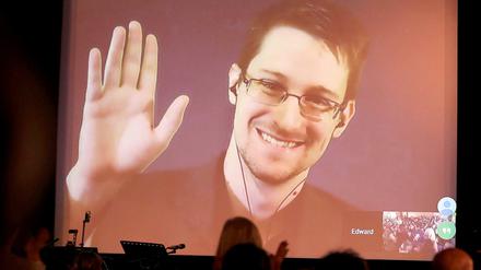 Der NSA-Enthüller Edward Snowden winkt im Dezember 2014 in Berlin während einer Videoschalte dem Publikum zu.