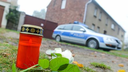 Eine Kerze, eine Blume und ein Polizeiwagen vor dem Haus des mutmaßlichen Entführers und Mörders von Mohamed und Elias.