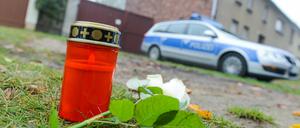 Eine Kerze, eine Blume und ein Polizeiwagen vor dem Haus des mutmaßlichen Entführers und Mörders von Mohamed und Elias.