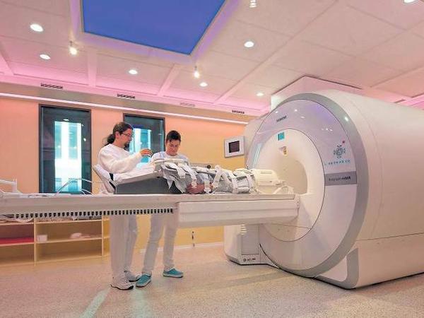 Medizinisches Personal schiebt einen Patienten in einen Kernspintomografen.