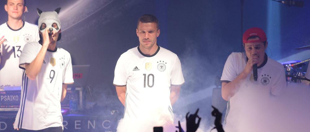 Lukas Podolski (M) posiert in Berlin mit Rapper Cro (l) bei der Trikot-Präsentation des DFB-Ausrüsters im neuen Trikots der deutschen Nationalmannschaft für die EM 2016 in Frankreich.