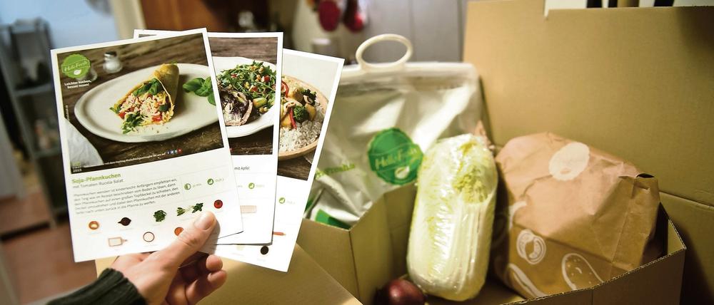 Ein Mann hält mitgelieferte Kochrezepte aus einer HelloFresh Kochbox in der Hand.