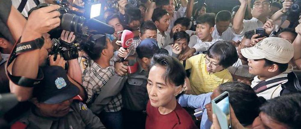 Lady in Red. Aung San Suu Kyi wird im Wahllokal von Medien umlagert.