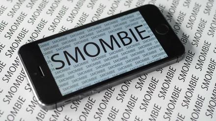 Das Wort "Smombie" ist am 13.11.2015 in München (Bayern) vielfach auf einem Smartphone und auf einem Zettel zu sehen. Der Langenscheidt-Verlag hat "Smombie" zum "Jugendwort des Jahres" gekürt. Es ist zusammengesetzt aus den Worten Smartphone und Zombie und beschreibt jemanden, der von seiner Umwelt nichts mehr mitbekommt, weil er nur noch auf sein Smartphone starrt.