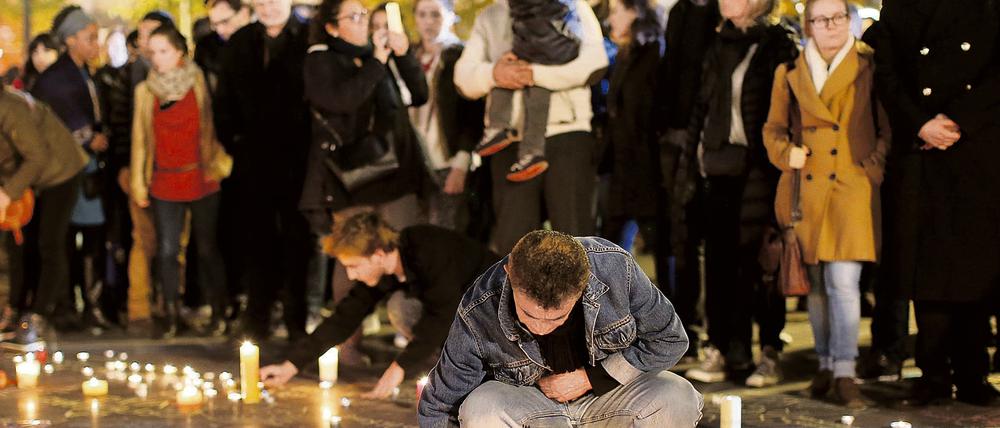 Menschen entzünden auf dem Platz der Republik in Paris Kerzen. Auch in privaten Wohnungen sollten Kerzen brennen, findet Tagesspiegel-Leserin Renate G., als verbindendes Zeichen.