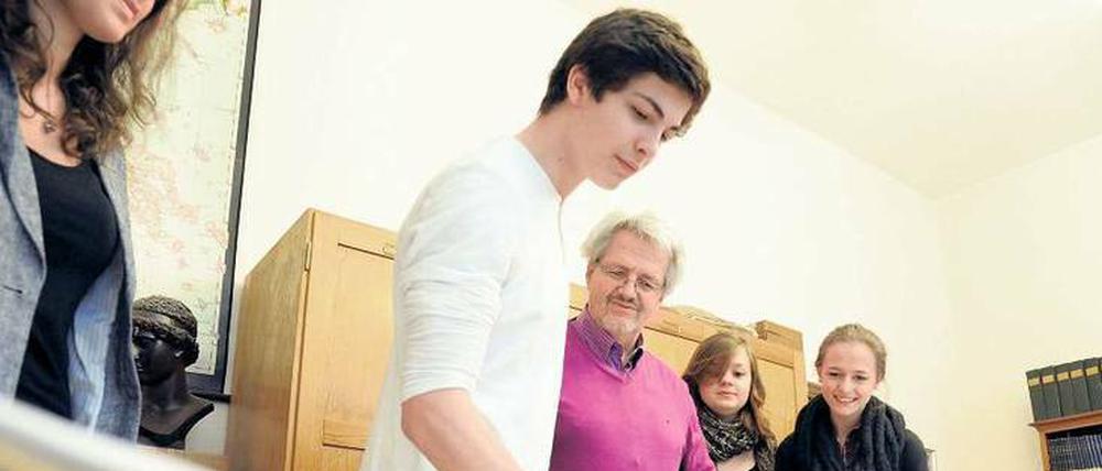 Ein Schüler schlägt mit einer Bürste auf ein Papier, das auf einer Steintafel liegt.