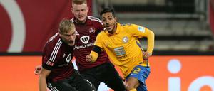 Die Nürnberger Hanno Behrens (links) und Sebastian Kerk sowie Braunschweigs Salim Khelifi haben den Ball im Blick. 