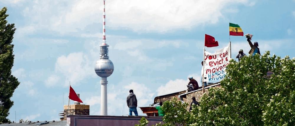 Seit dem Sommer 2014 ist die Gerhart-Hauptmann-Schule in Kreuzberg von Flüchtlingen besetzt. Hier sieht man einige bei Protesten auf dem Dach im Juni desselben Jahres.