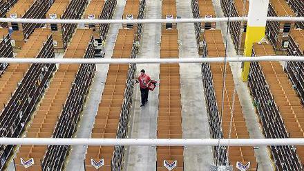 Allein auf schmaler Flur stellt ein sogenannter „Picker“ in Brieselang (Kreis Havelland) im Lager des Amazon-Logistikzentrums die Bestellungen zusammen. Foto: Bernd Settnik/dpa