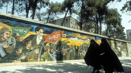 Verschleierte Iranerinnen neben einem Wandgemälde mit dem Konterfei von Ayatollah Khomeini in Teheran, 1984. In dieser Zeit spielt Deborah Ellis' Roman "Wenn der Mond am Himmel steht, denk ich an dich". 