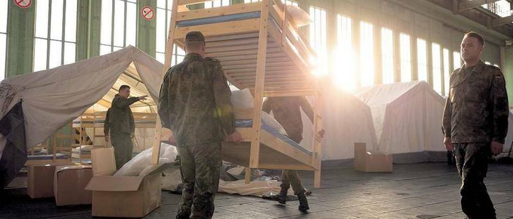 THW-Helfer und Bundeswehr-Soldaten richten gemeinsam eine Flüchtlingsunterkunft im alten Berliner Flughafen Tempelhof ein.