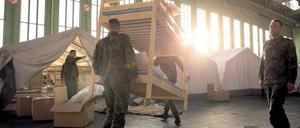 THW-Helfer und Bundeswehr-Soldaten richten gemeinsam eine Flüchtlingsunterkunft im alten Berliner Flughafen Tempelhof ein.