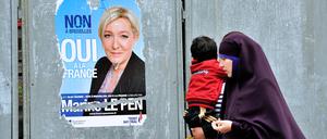 Passantinnen mit einem Jungen gehen im nordfranzösischen Valenciennes an einem Plakat der Front-National-Chefin Marine Le Pen vorbei.
