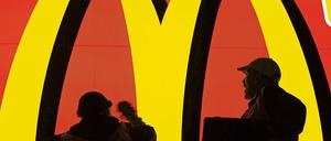 Zwei Arbeiter stehen auf einem Hubwagen und reinigen eine große Werbefläche der Fastfood-Filiale McDonald's im Hauptbahnhof in Frankfurt am Main