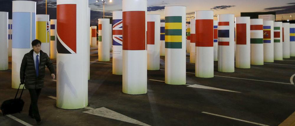 Durch diese Säulen mit den Länderflaggen gehen die Delegierten beim Pariser Klimagipfel jeden Morgen. Viele kommen, solange es noch dunkel ist und verlassen das Gelände nachts wieder.