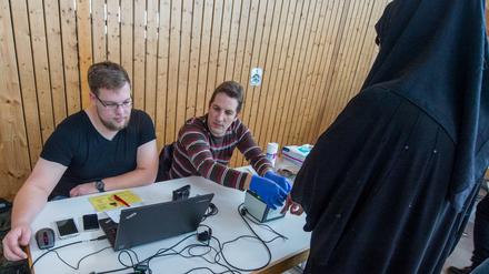 Soldaten in Zivilkleidung helfen bei der Registrierung von Flüchtlingen.