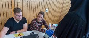 Soldaten in Zivilkleidung helfen bei der Registrierung von Flüchtlingen.