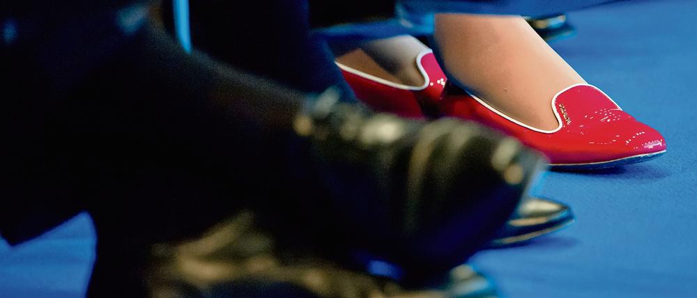 Die roten Schuhe einer Teilnehmerin des Tages der Industrie sind am 11.06.2013 in Berlin zwischen den Beinen von Männern in dunklen Anzügen und passendem Schuhwerk zu sehen. Die 30 Dax-Konzerne sind nach einem Bericht des Arbeitgeberverbandes BDA von ihren selbst gesteckten Zielen für mehr Frauen in Spitzenpositionen teils noch weit entfernt.