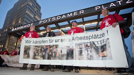 Mitarbeiter des Bahnwerks Eberswalde halten während einer Mahnwache für den Erhalt ihrer Arbeitsplätze am 05.10.2015 auf dem Potsdamer Platz in Berlin (Deutschland) ein Transparent mit der Aufschrift «Wir kämpfen für unsere Arbeitsplätze!» in den Händen. 
